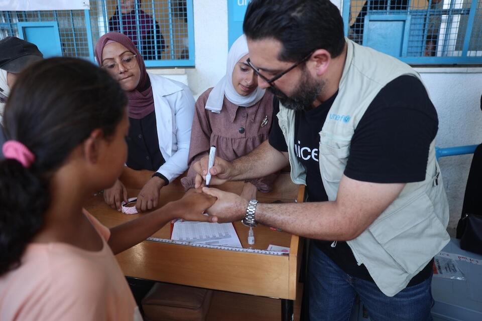 A UNICEF vaccinator marks the finger of a child in Khan Younis, Gaza Strip, to show she has received a dose of polio vaccine. 