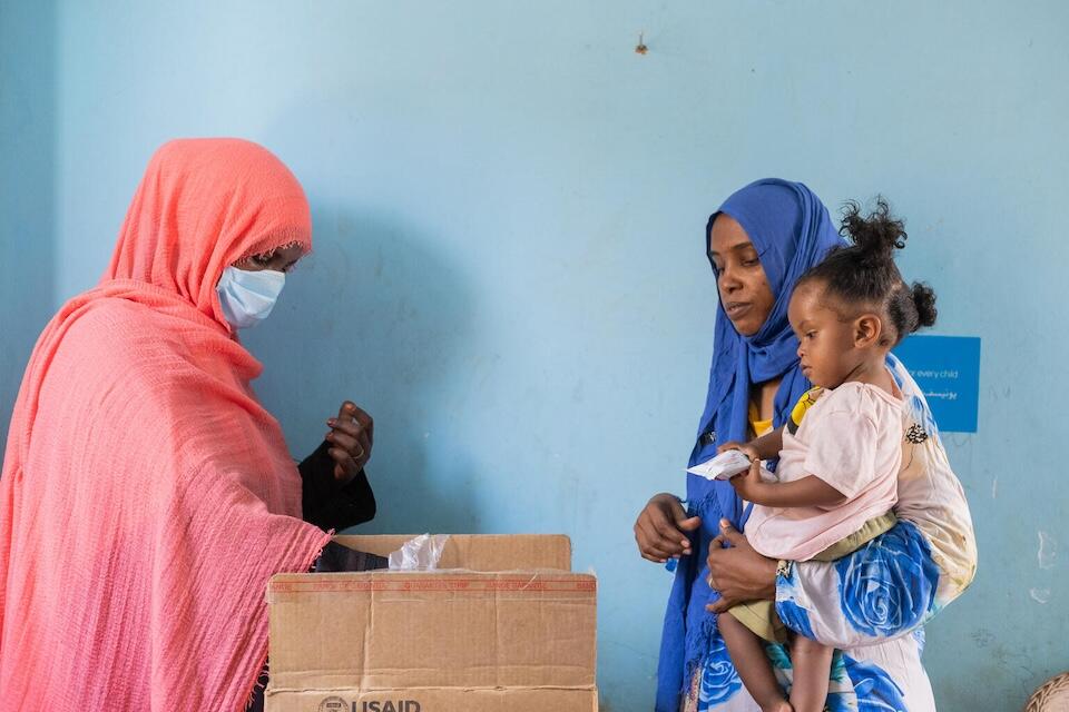 A displaced mother from Khartoum  receives sachets of Ready-to-Use Therapeutic Food (RUTF) at a UNICEF-supported mobile clinic in Adama locality, Atbara, River Nile State, Sudan.