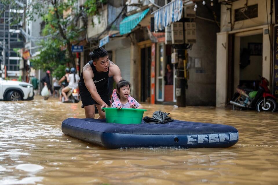 A young girl is carried home by her father on a mattress in Hoan Kiem District, Hanoi on Sept. 11, 2024. 