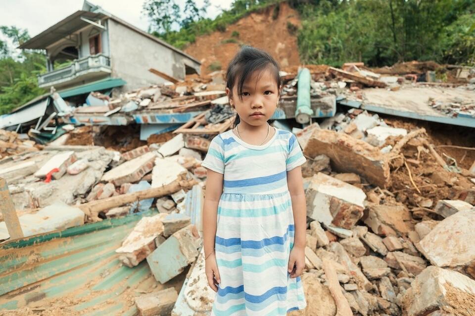 Six-year-old Cao Huyền Trang stands in front of her home, destroyed by a landslide caused by Super Typhoon Yagi’s heavy rains.