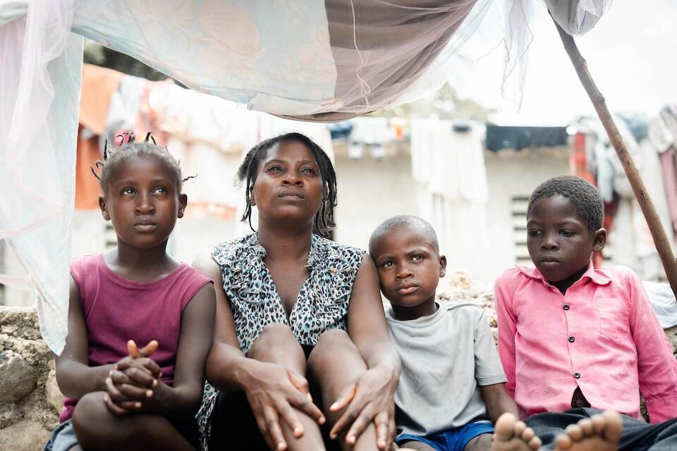 A mother and her three children sit under a tent at a camp for displaced families in Léogâne, a coastal commune in southwestern Haiti.