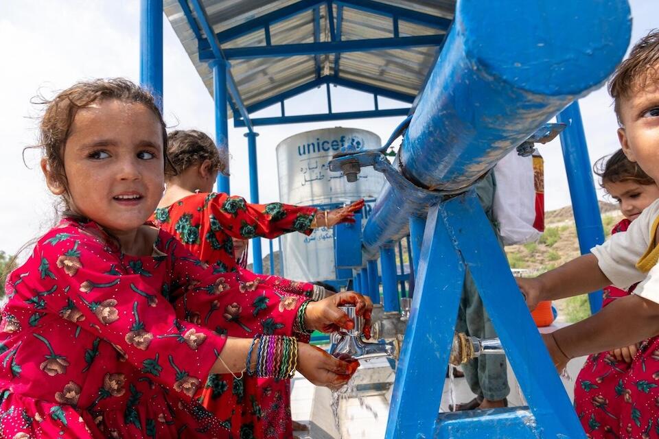 On Aug. 4, 2024, in Torkham, Nangarhar province, Afghanistan, a girl washes her hands and face using water from a UNICEF-supported system powered by a solar pump and reservoir located on the nearby hill. 