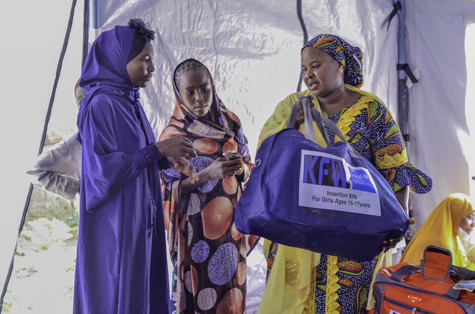 At a UNICEF-supported camp in Maiduguri, Nigeria, a hygiene kit is given to two adolescent girls displaced by severe flooding.