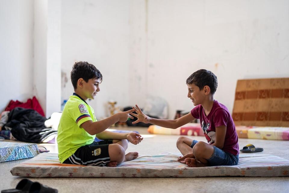 Two young boys play together on the floor at a public school that has become a shelter for families displaced by escalating conflict in Lebanon.