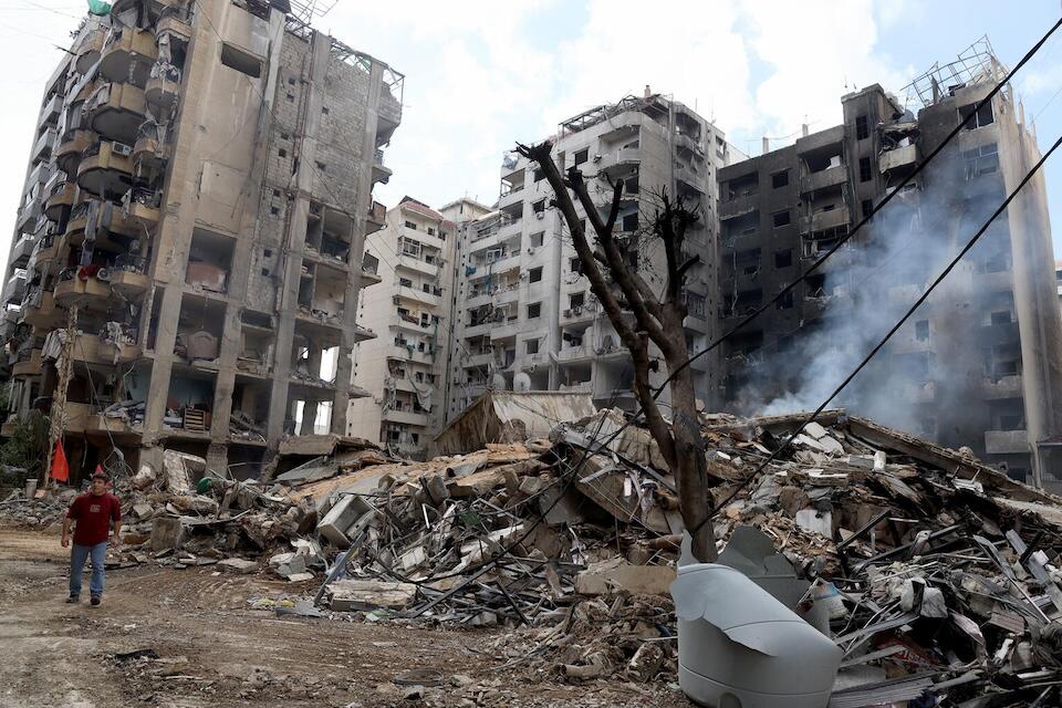 Surrounded by debris, people inspect the rubble of buildings leveled by air strikes that targeted the neighborhood of Beirut’s southern suburbs on Oct. 1, 2024.