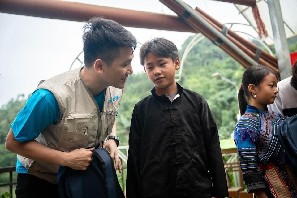 UNICEF Education Officer, Tung Hoang Nguyen, gives a UNICEF-supplied school backpack to Thao Seo Ha, 11, after Typhoon Yagi hit Vietnam in September 2024..