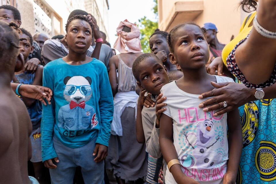 Children displaced by violence in Haiti queue for food at a humanitarian relief distribution site supported by UNICEF.