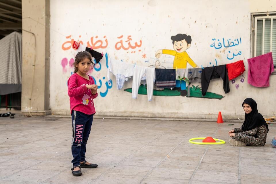 Zahraa, 6, stands near another displaced girl from Beirut southern suburbs in a courtyard outside the public school turned shelter where their families have been staying since escalating conflict forced them to flee their homes.