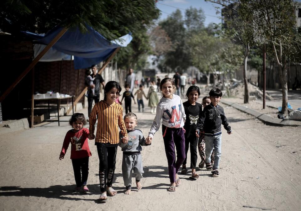 A group of children walk down the road holding hands in Khan Younis, Gaza Strip. 