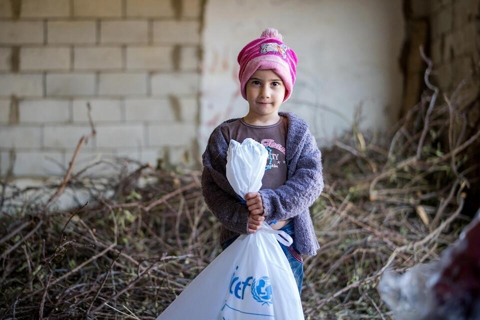 On Dec. 27, 2023, a child holds a bag of winter clothes delivered by UNICEF to displaced children in Lebanon.