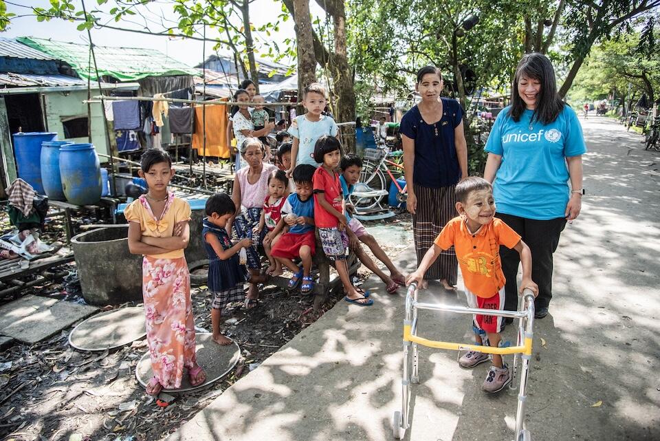 With support from UNICEF and partners, a 5-year-old boy with disabilities is able to walk outide his home in Dala Township, Yangon, Myanmar, using a walker and ankle foot orthoses. 