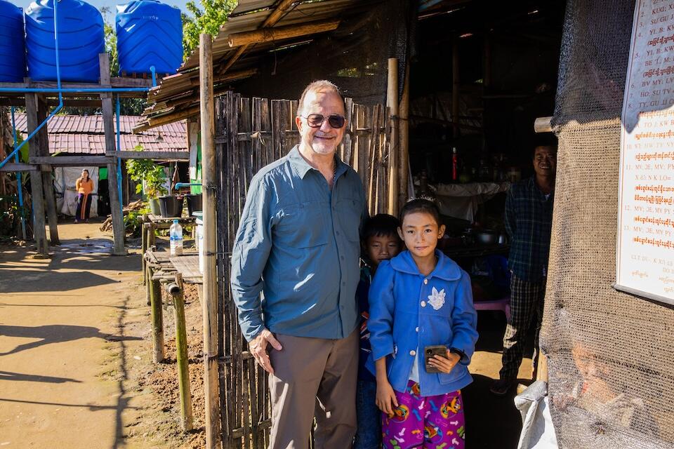 Ted Chaiban, Deputy Executive Director of UNICEF, stands with children outside their temporary room at the Shamari camp for displaced families during a visit to Myitkyina, Kachin State, Myanmar, Nov. 14, 2024.