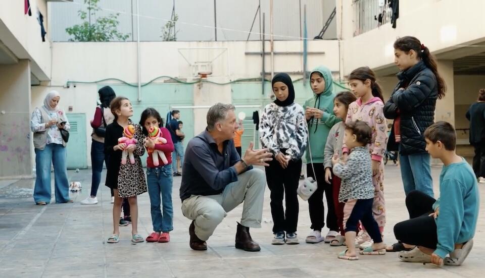 UNICEF spokesperson James Elder kneels besides a group of young children staying at a UNICEF-supported shelter in Beirut for families displaced by conflict.