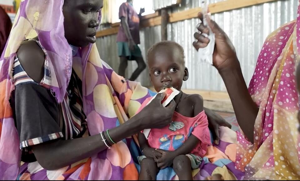 In South Sudan, a mother feeds her young child Ready-to-Use Therapeutic Food (RUTF), a fortified peanut paste supplied by UNICEF to treat severe acute malnutrition.