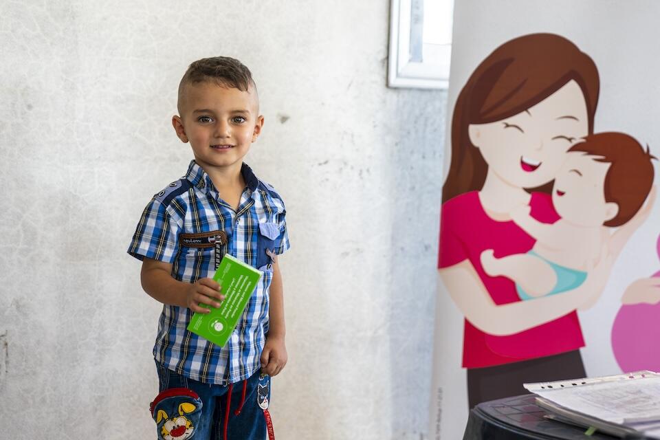 Ammar, 3, holds his box of nutrition supplies provided by a UNICEF-supported health and nutrition mobile clinic in Ghawr Al-Assi village, in rural Hama, Syria, on July 10, 2024.