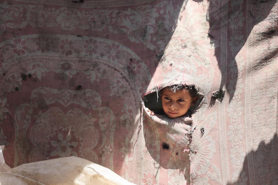 Jasser, 7, looks out of one of the broken walls of a tent in the Gaza Strip on Sept. 1, 2024.