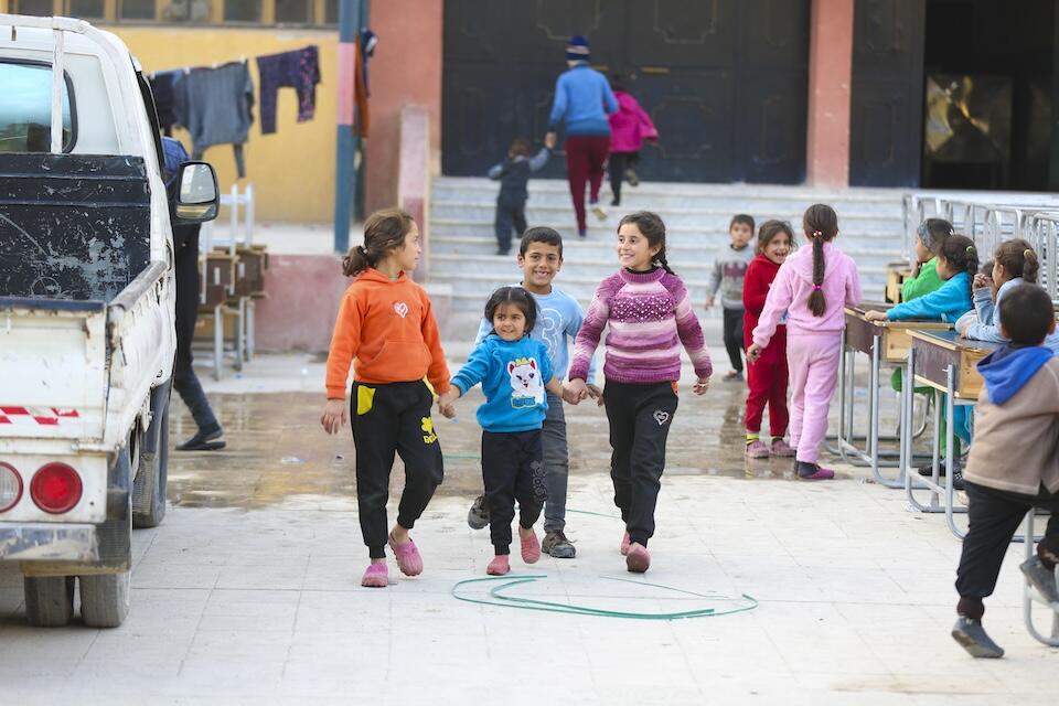 Children walk hand-in-hand outside a UNICEF-supported shelter for displaced families in Ar-Raqqa city, Syria, on Dec. 4, 2024. 