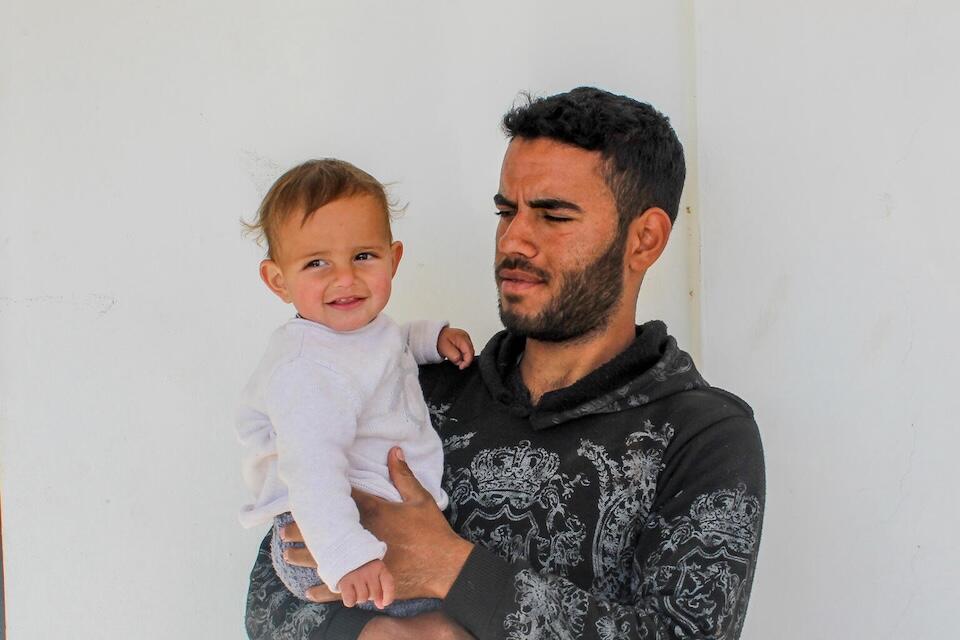 A father holds his 1-year-old son in in their home in Obada village, Rural Damascus, Syria on Dec. 17, 2024.