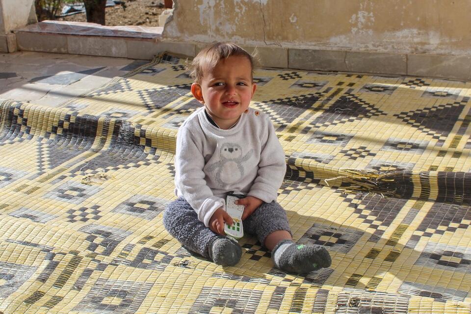 One-year-old Morei sits on a carpet in the yard of his home in Obada village, Rural Damascus, Syria on Dec. 17, 2024.