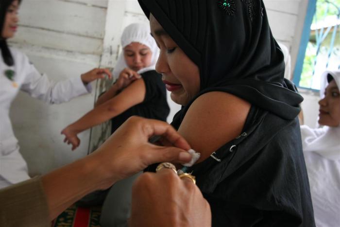 A woman&#039;s arm is swabbed by a health worker following a tetanus vaccination in the village of Semeureung, Indonesia. © UNICEF/Estey