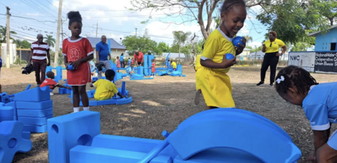 Children from National Water Commission Credit Union Basic School playing with blue blocks at the pop-up playground supported by UNICEF.