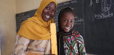  A UNICEF-supported teacher and one of her students stand in front of the chalkboard at a school in Mali.