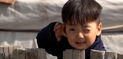 J. Khuvituguldur, 4, peeks over the fence behind his family's ger home in the outskirts of Ulaanbaatar, Mongolia.