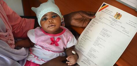 Fatima Mahamat, 20, holds her 23-day-old baby girl Amina in her lap and the child's new birth certificate in her hand, having completed the registration in just a few minutes using a digital app, at the health center in N’Djamena, the capital of Chad, where the child was vaccinated.