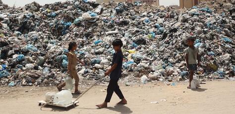 Children pass through a waste dump while searching for clean,safe drinking water in Rafah, southern Gaza Strip.