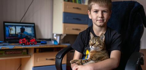 Nine-year-old Andrii holds his cat in his bedroom in Kherson, Ukraine. 