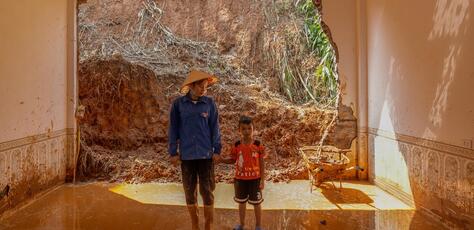 A mother and son stand inside their flooded home in Lao Cai province, Vietnam after Super Typhoon Yagi.