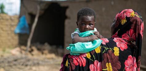 A mother holds her 2-month-old infant outside the flood-damaged family home in Sirebougou village, Ségou region, Mali.