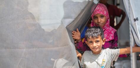 In Al-Khawkhah district, Al-Hudaydah governorate, Yemen, a brother and sister step outside a tented classroom where children affected by conflict are able to resume their education with UNICEF support.