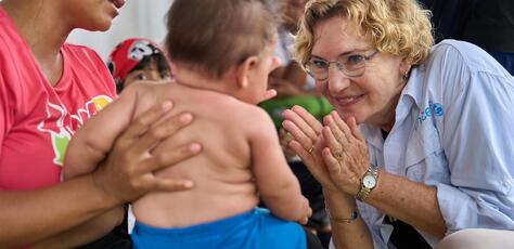 Karin Hulshof, UNICEF Regional Director in Latin America and the Caribbean, plays with a baby at a respite center for migrating families in Darien, Panama.