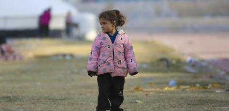 On Dec. 4, 2024, in Ar-Raqqa city, Syria, a young girl stands outside a UNICEF-supported reception center for families displaced by escalating violence in Aleppo.