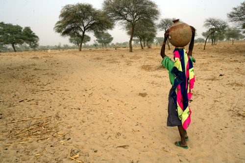 A girl in Niger carries a jug of water to her home in the region of Maradi
